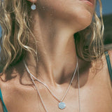 silver pendant being worn on beach